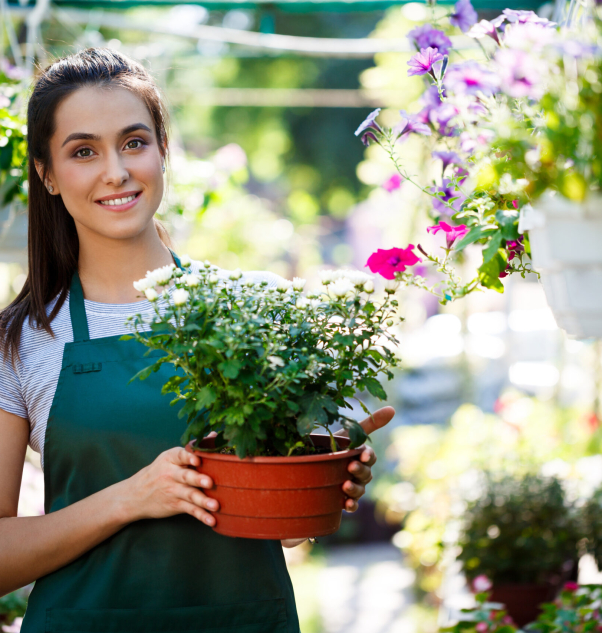 Young beautiful female florist posing, smiling among flowers.